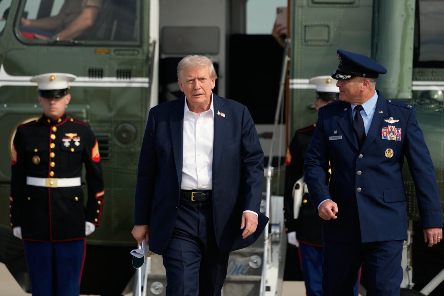President Donald Trump, center, is escorted by Air Force Col. Christopher M. Robinson, commander of...