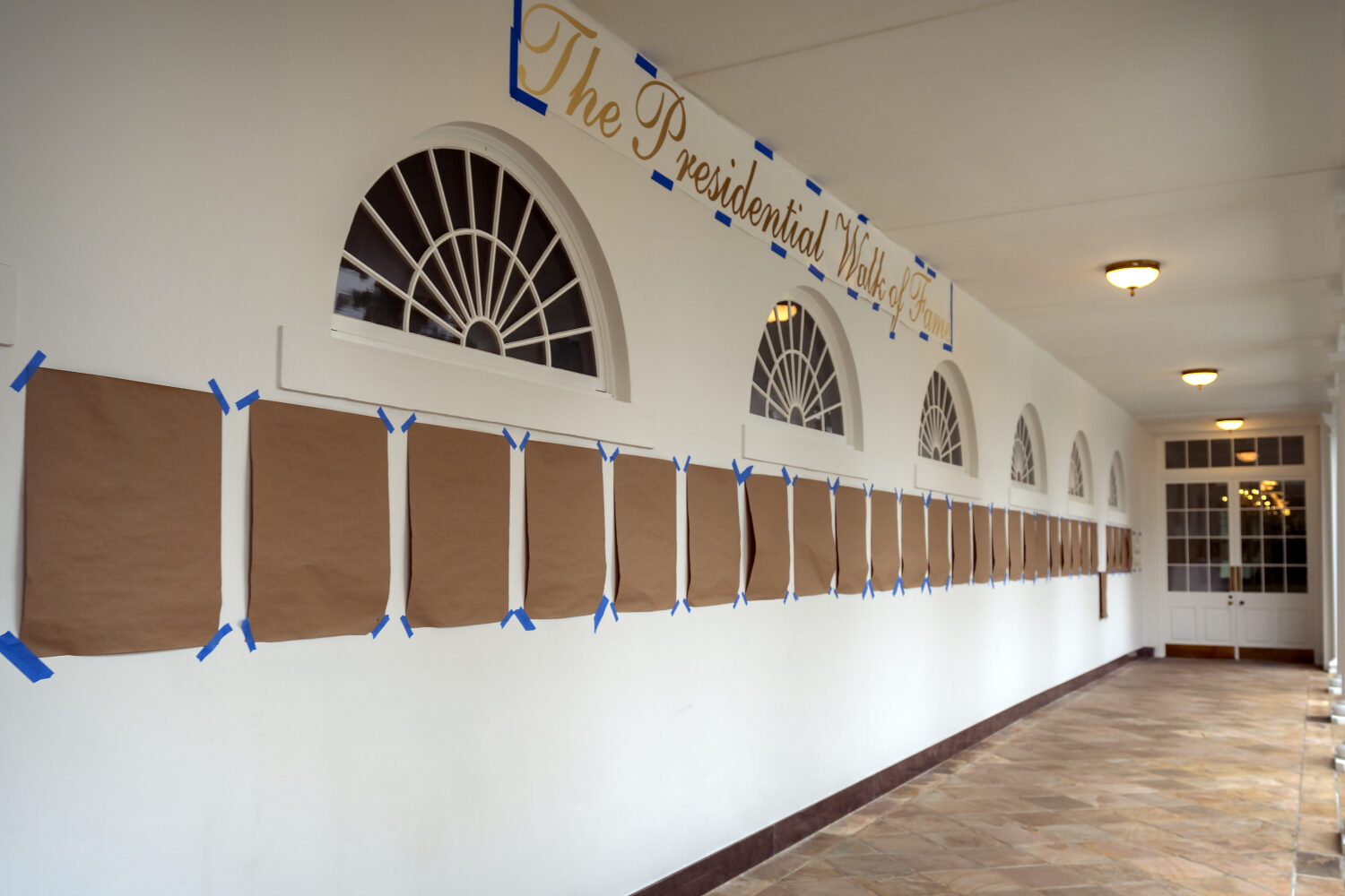 A sign reading "The Presidential Walk of Fame" and pieces of brown paper are taped along the wall o...