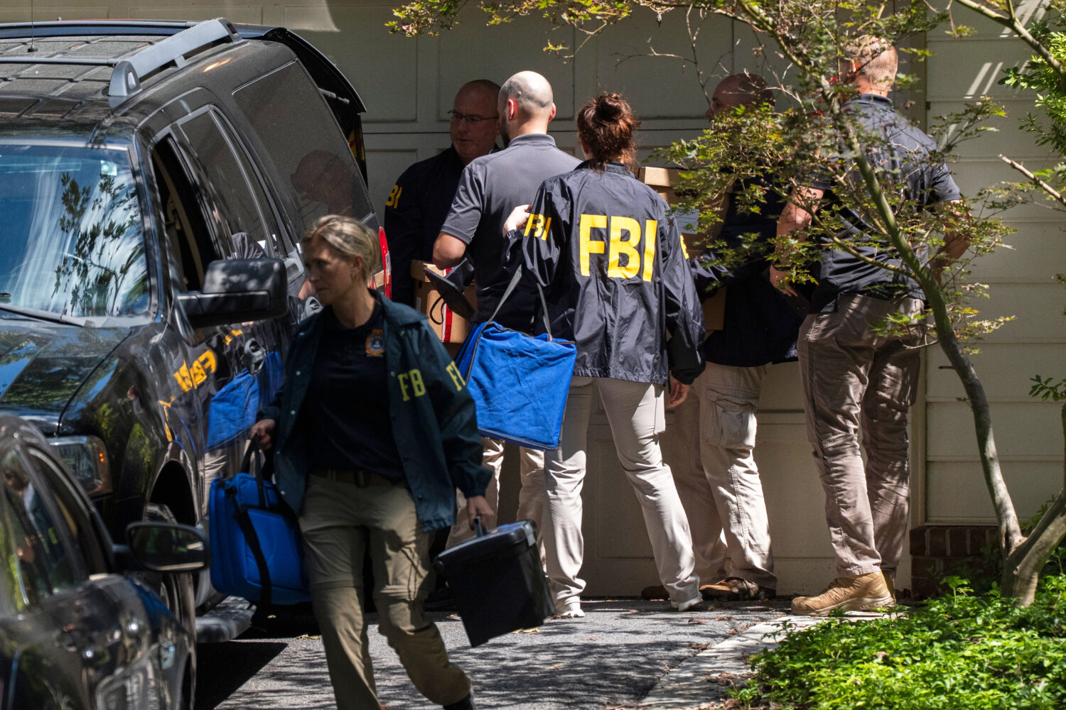 FBI agents carry bags and boxes out of former national security adviser John Bolton's house Friday,...