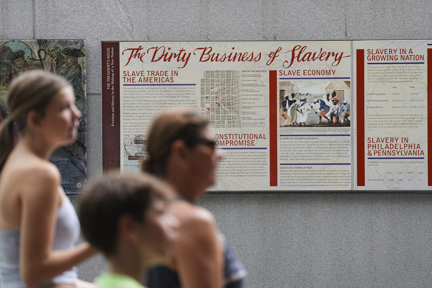 People walk past an informational panel at President's House Site Tuesday, Aug. 19, 2025, in Philad...