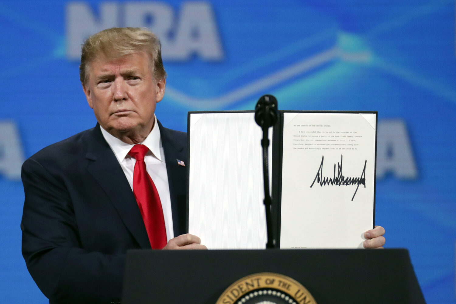 FILE - President Donald Trump holds a document with his signature as he speaks at the Nation Rifle ...