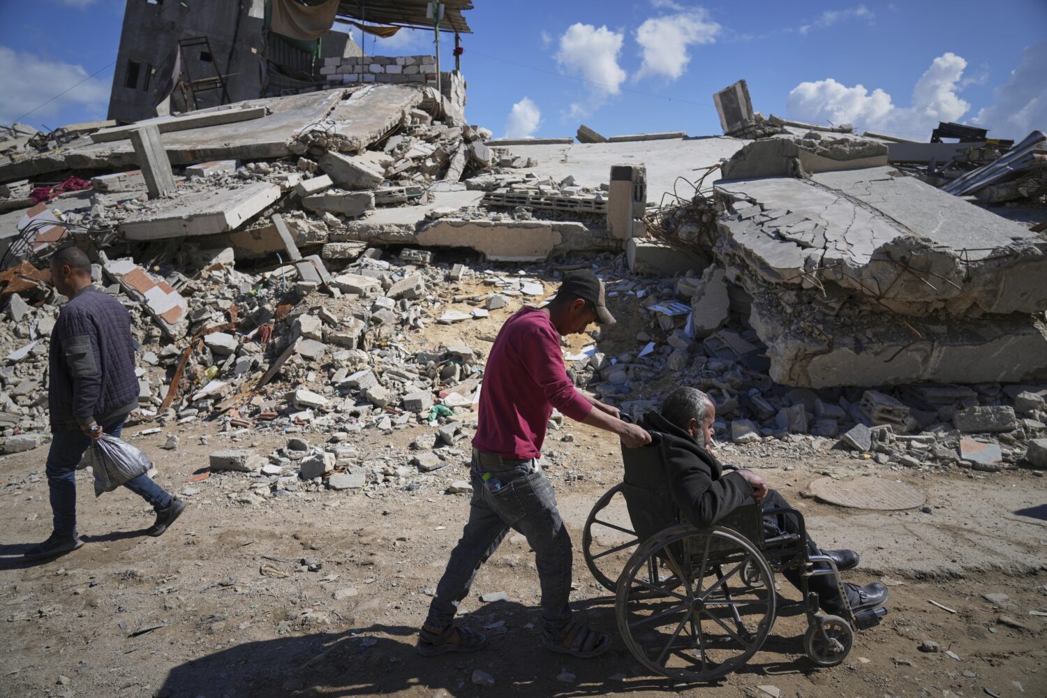 FILE - Wasem Attiya pushes his father, Mohamed, 54, in a wheelchair as they head to Shifa hospital ...