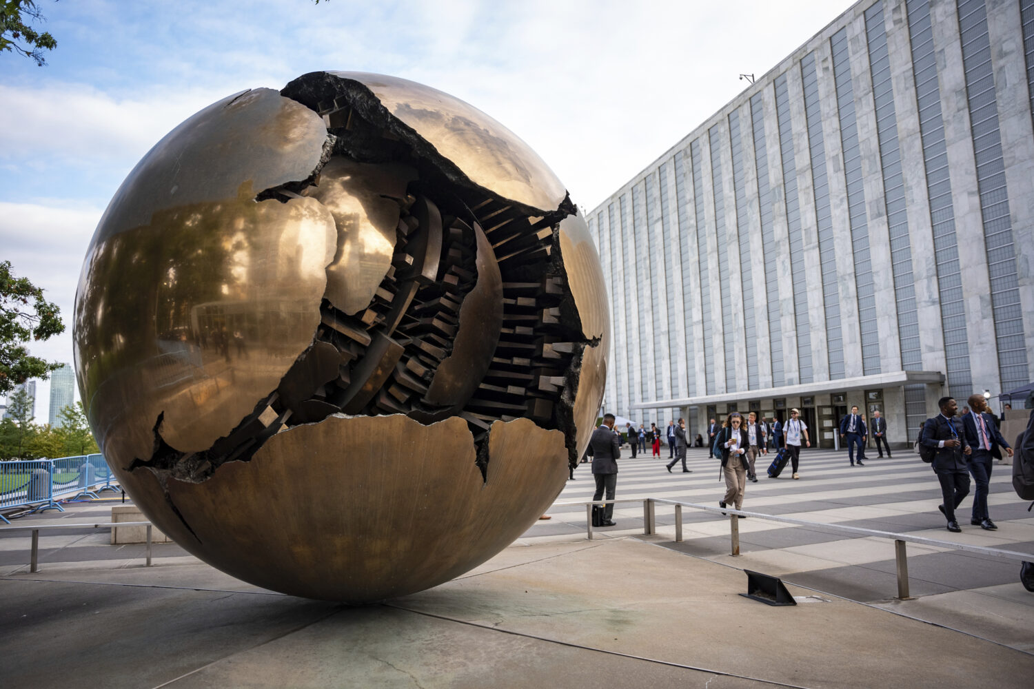People walk around the plaza by the Sphere Within Sphere outside the United Nations Headquarters on...
