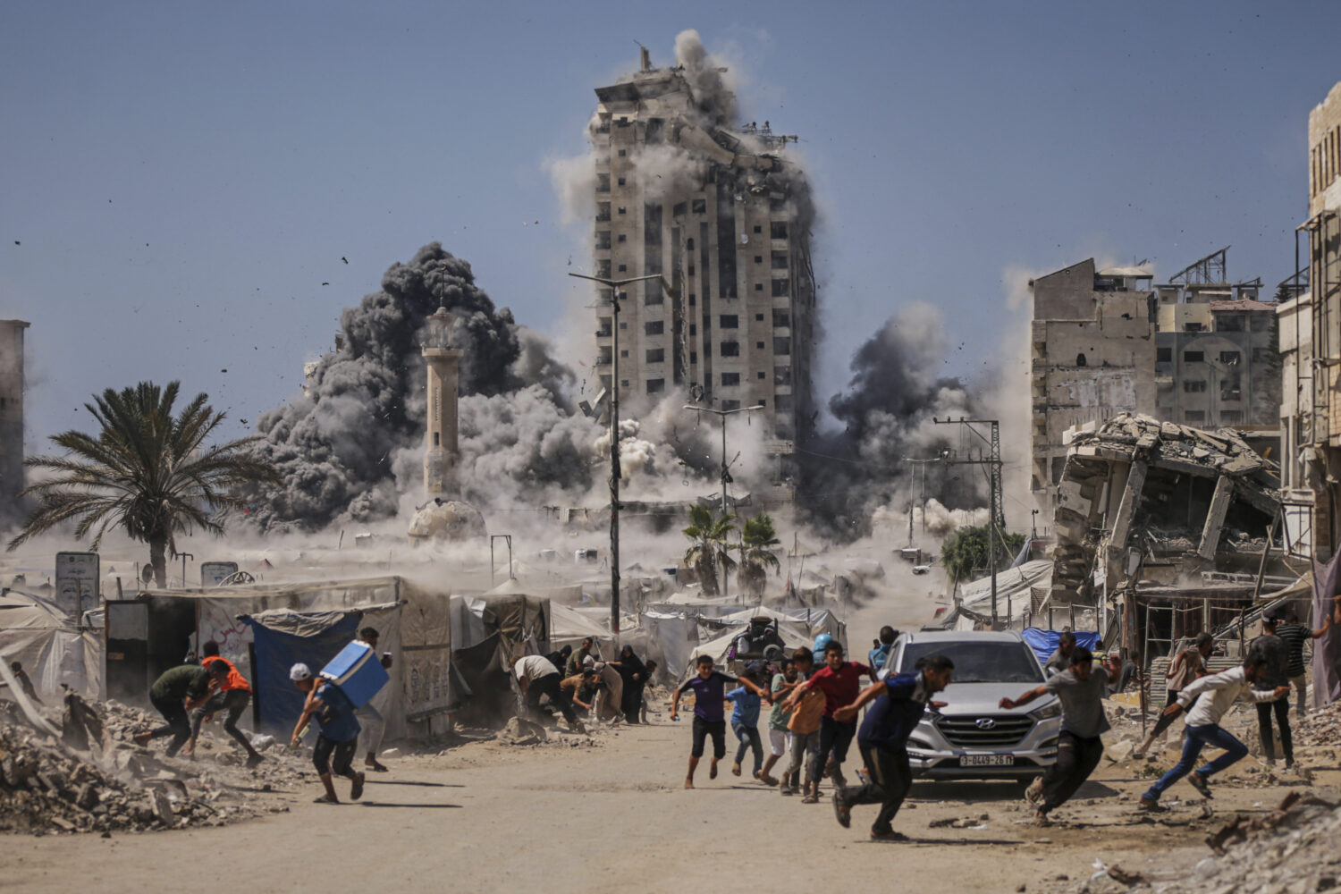 FILE - Palestinians run for cover during an Israeli airstrike on a high-rise building in Gaza City,...