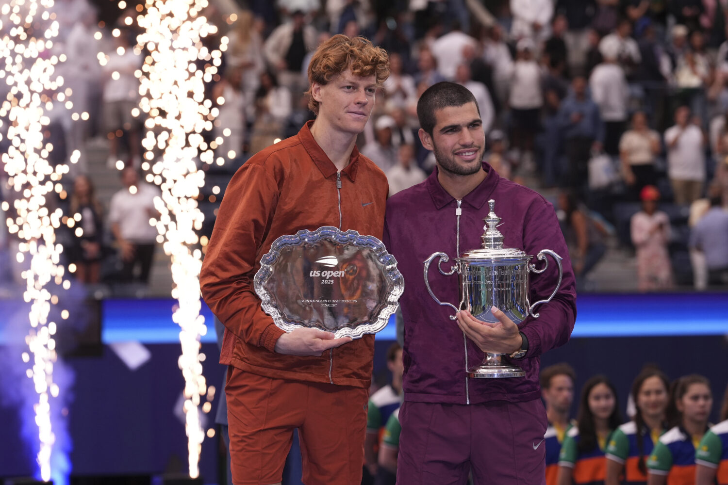 Jannik Sinner, of Italy, left, and Carlos Alcaraz, of Spain, right, hold their trophies after Alcar...