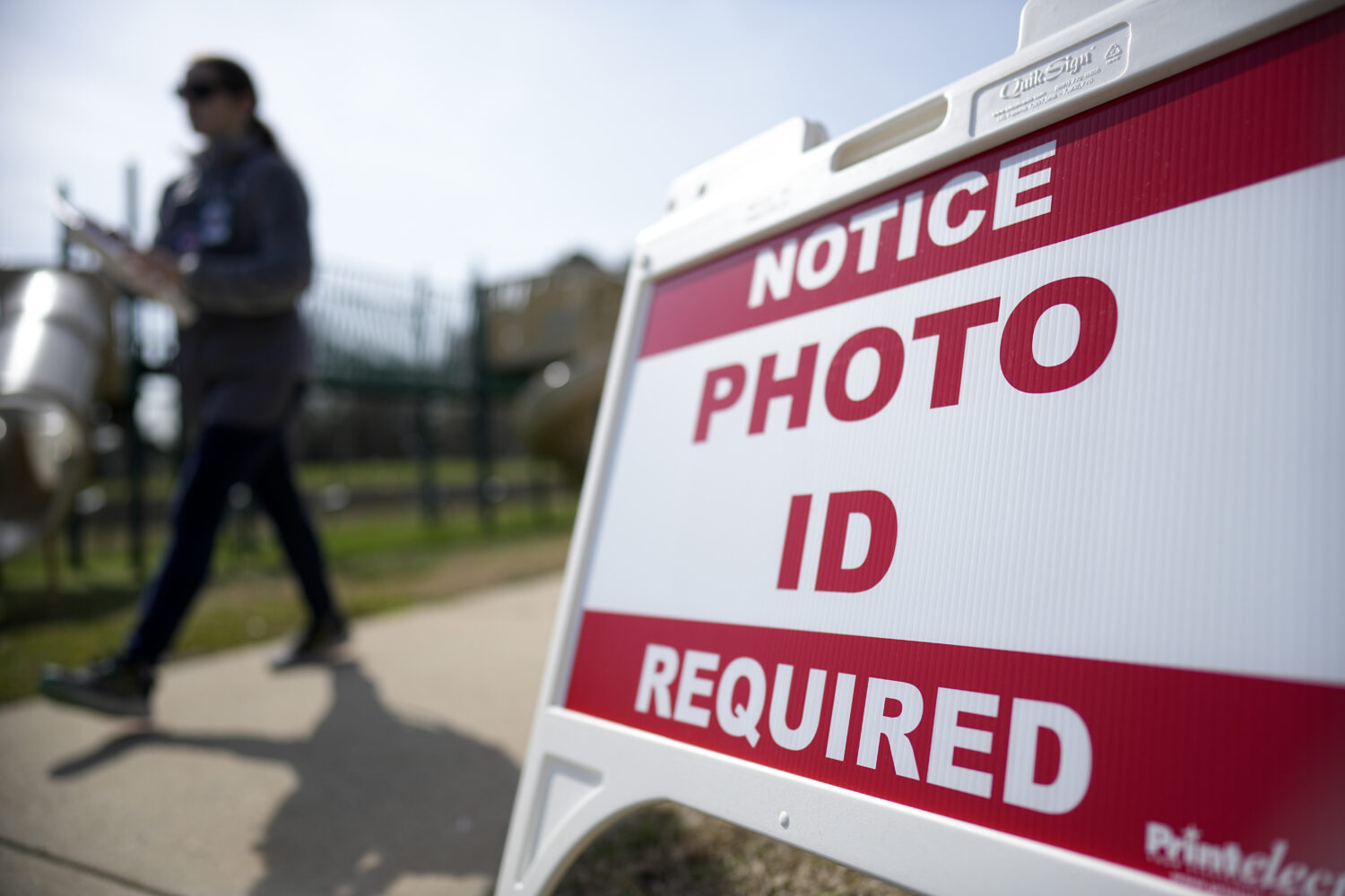 FILE - A Super Tuesday voter walks past a sign requiring a photo ID at a polling location, March 5,...