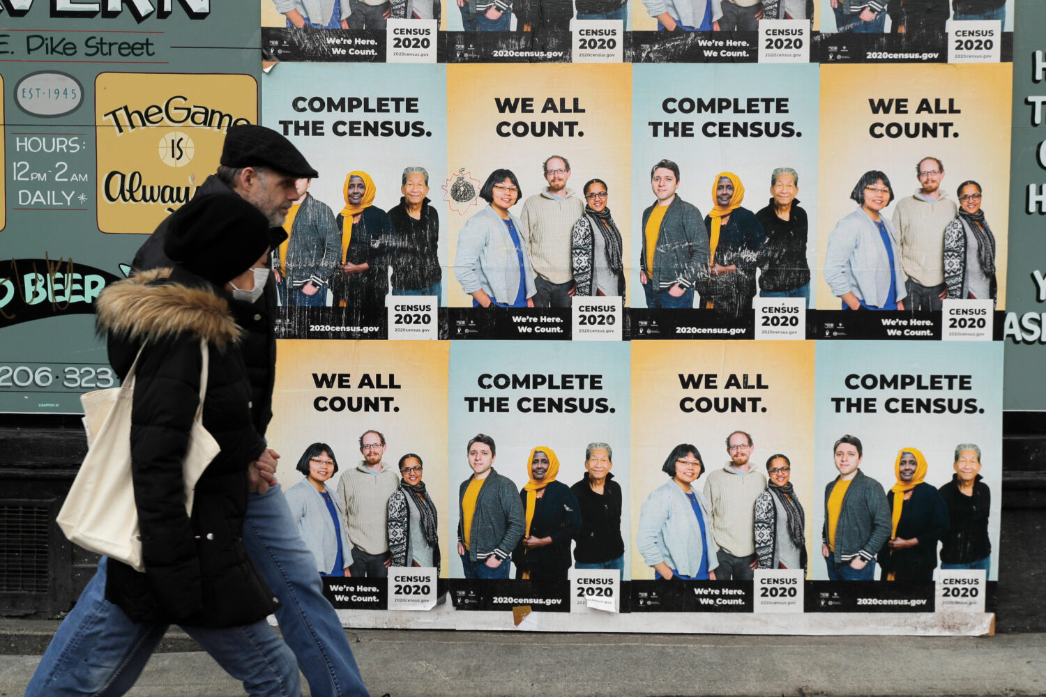 FILE - In this Wednesday, April 1, 2020 file photo,People walk past posters encouraging participati...