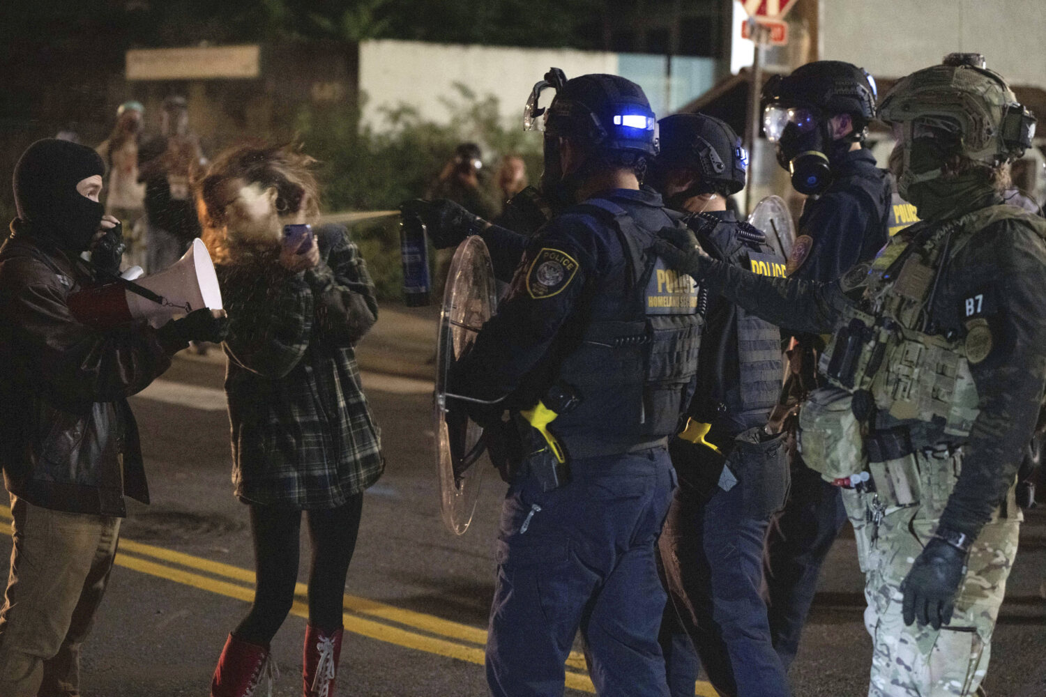 A protester is sprayed by a Department of Homeland Security officer outside a U.S. Immigration and ...