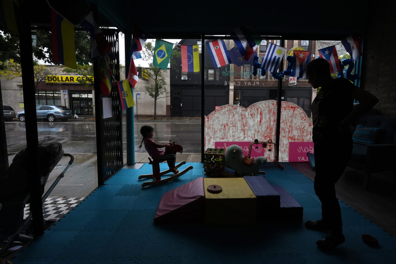 A girl rides a rocking horse as her grandmother looks o inside Luna y Cielo Play Cafe in Chicago's ...