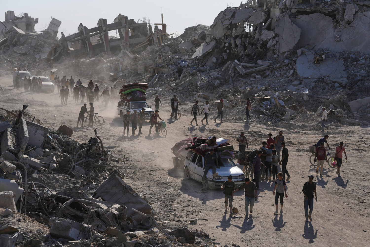 Displaced Palestinians with their belongings pass by destroyed buildings as they return to their ho...