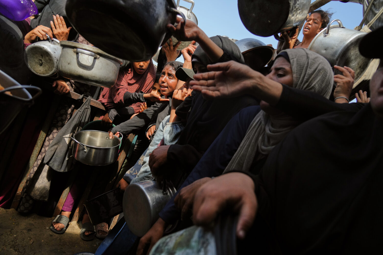 Palestinians struggle to get donated food at a community kitchen in Khan Younis, southern Gaza Stri...