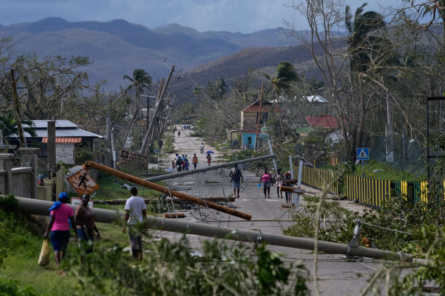 Residents walk through Lacovia Tombstone, Jamaica, in the aftermath of Hurricane Melissa, Wednesday...