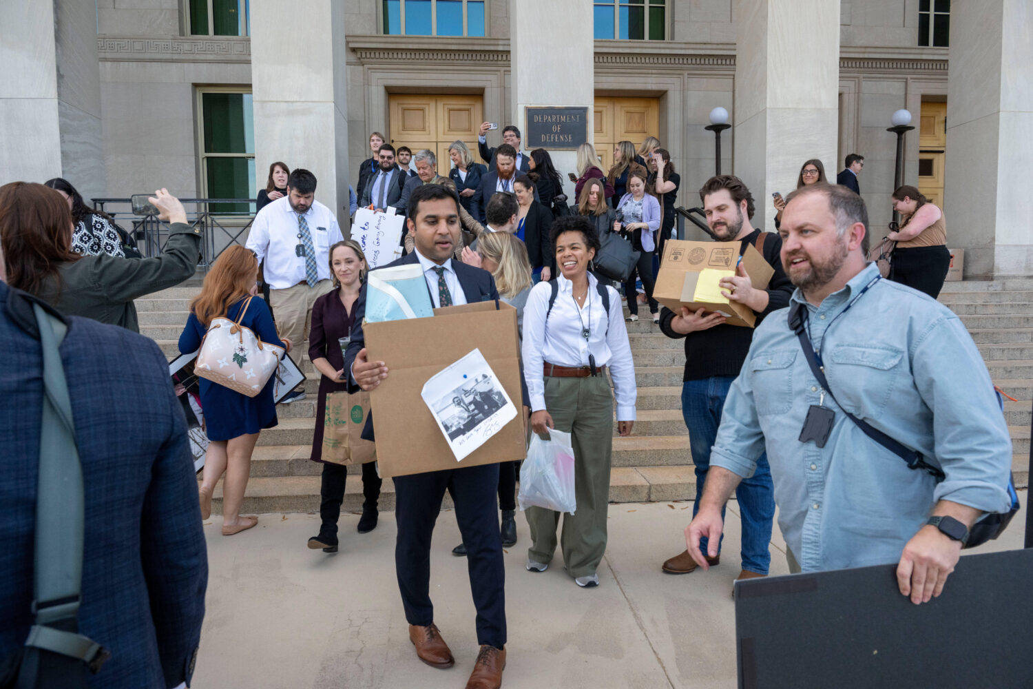 Members of the Pentagon press corp carry their belongings out of the Pentagon after turning in thei...