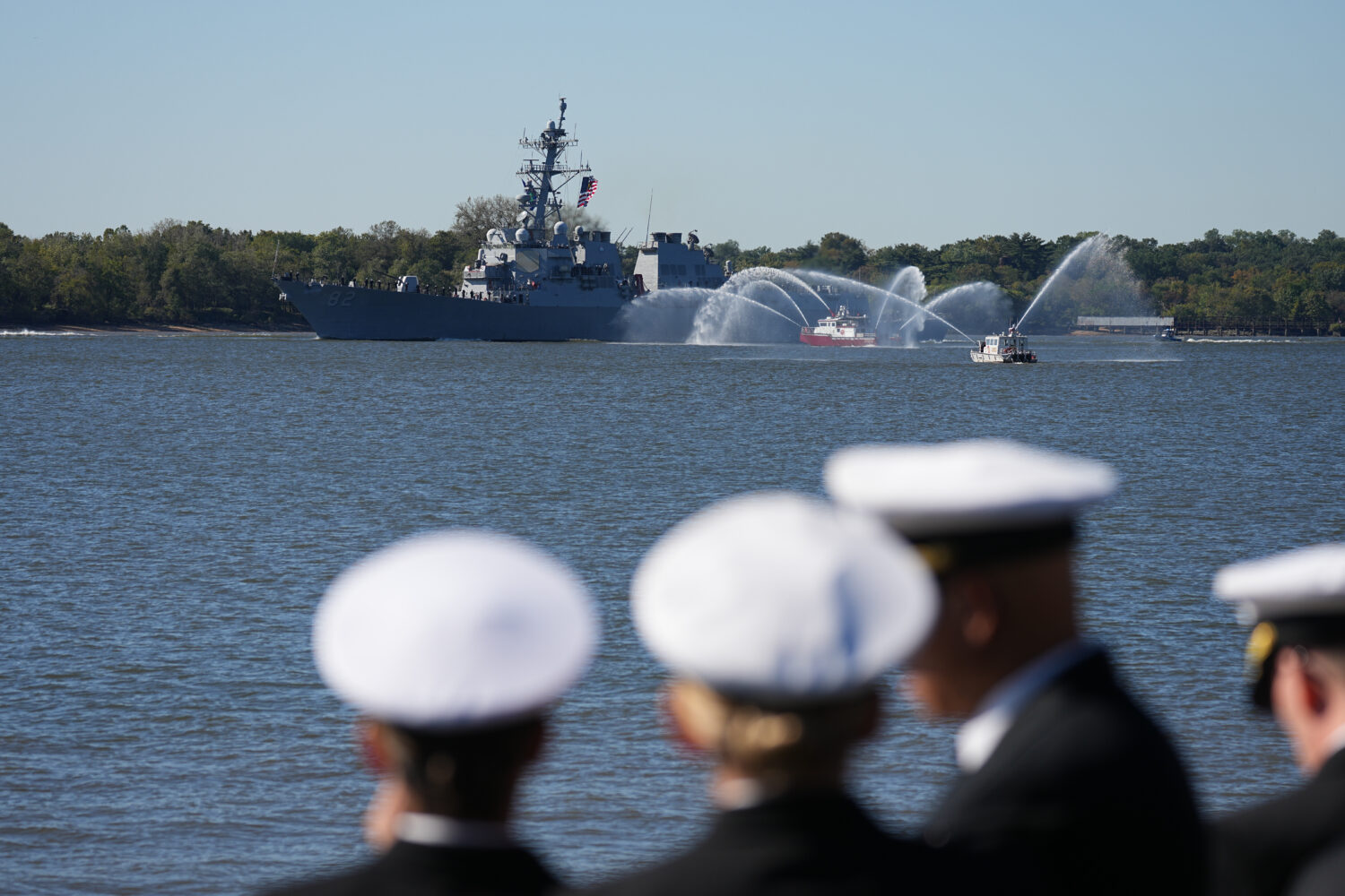 Spectators look on as U.S. Navy ships pass the viewing stand during the 250th anniversary of the fo...