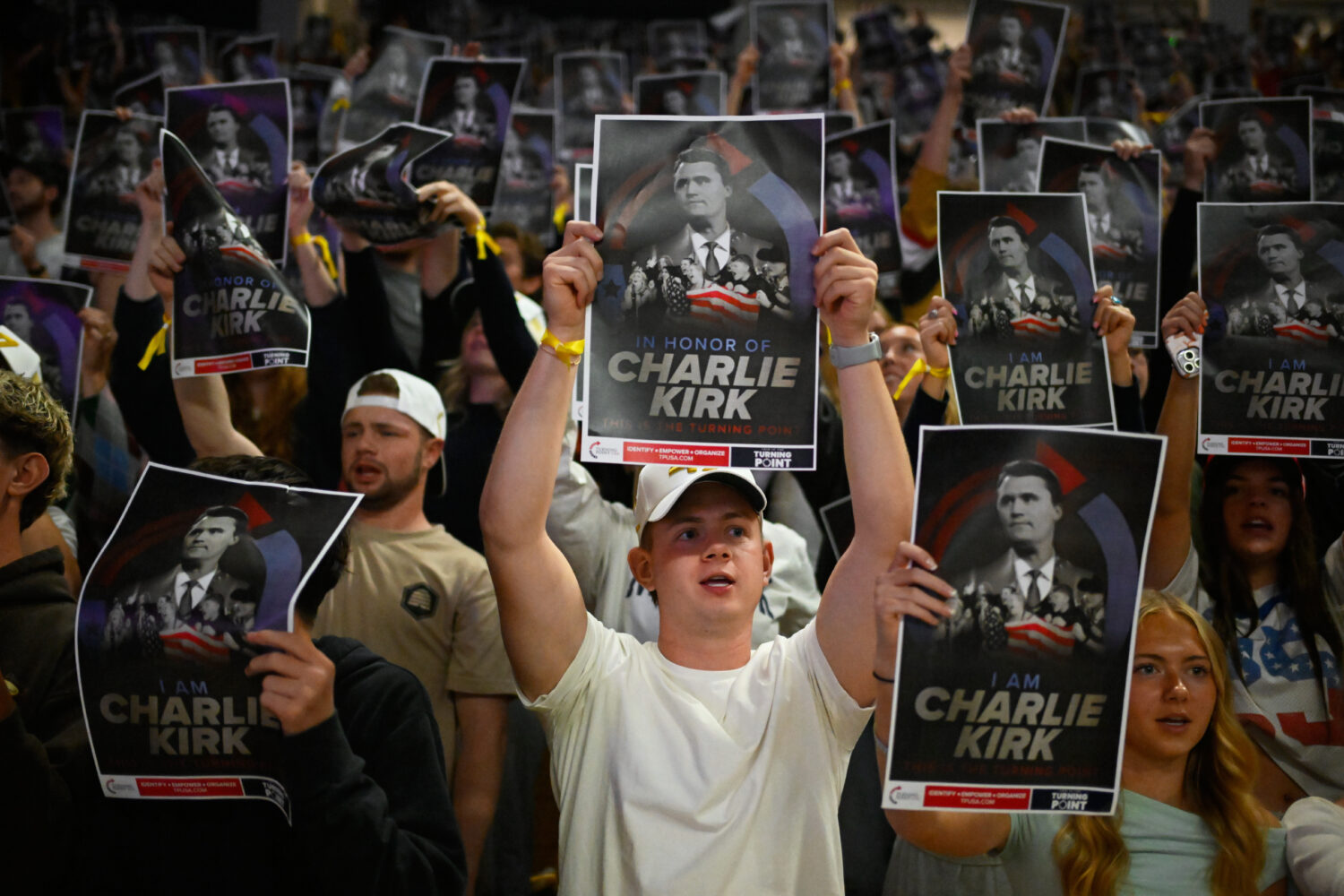 People hold posters of Charlie Kirk during a Turning Point USA rally at Utah State University, as a...