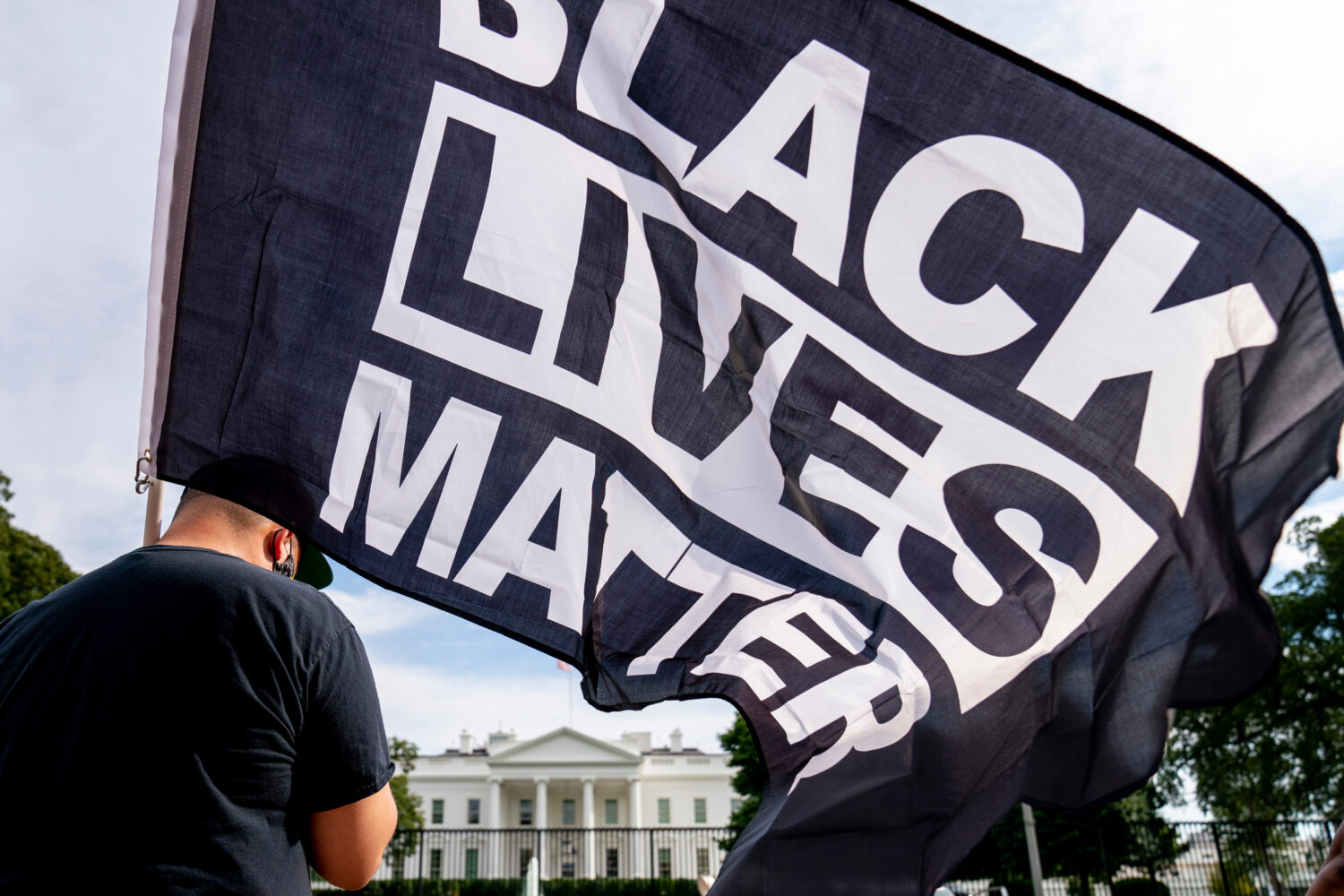 FILE - A man carries a Black Lives Matter flag in Lafayette Square outside the White House on the f...