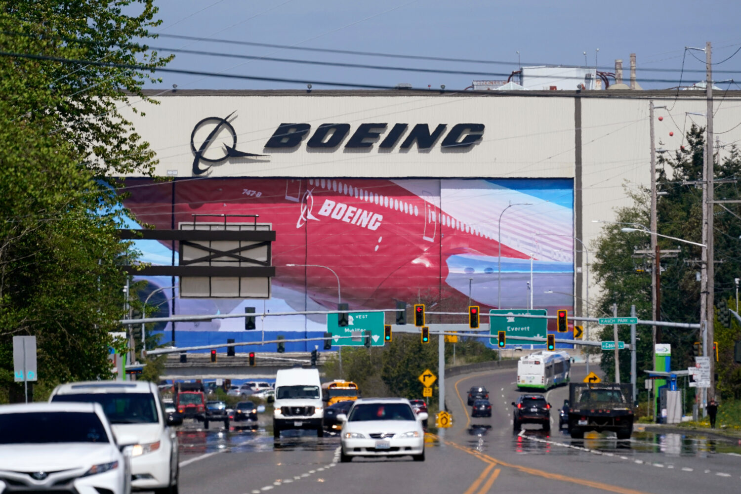 FILE - Traffic drives in view of a Boeing Co. production plant, where images of jets decorate the h...