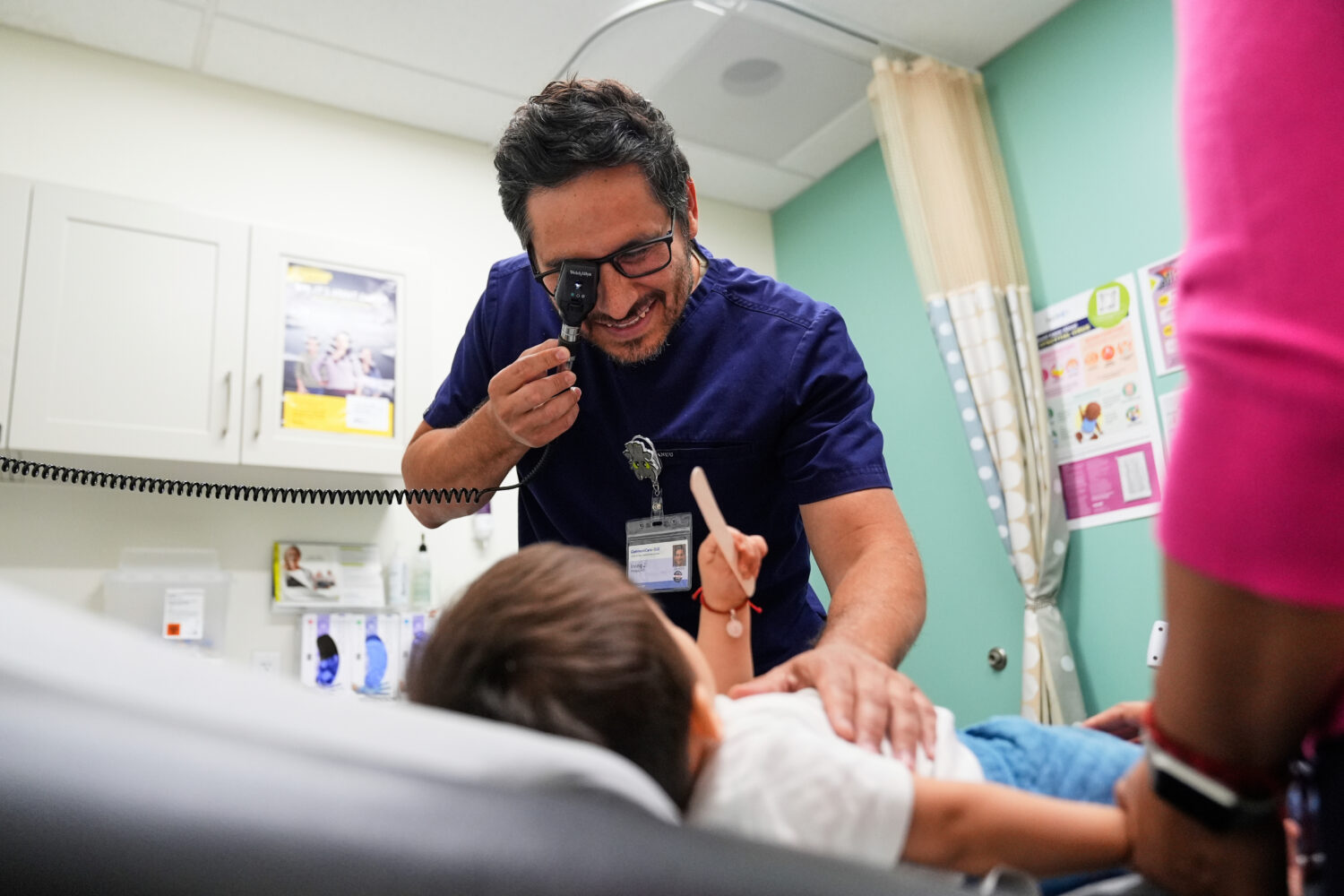 FILE - Pediatrician Irving Phillips, left, examines a 16-month-old boy at a CommuniCARE+OLE clinic,...
