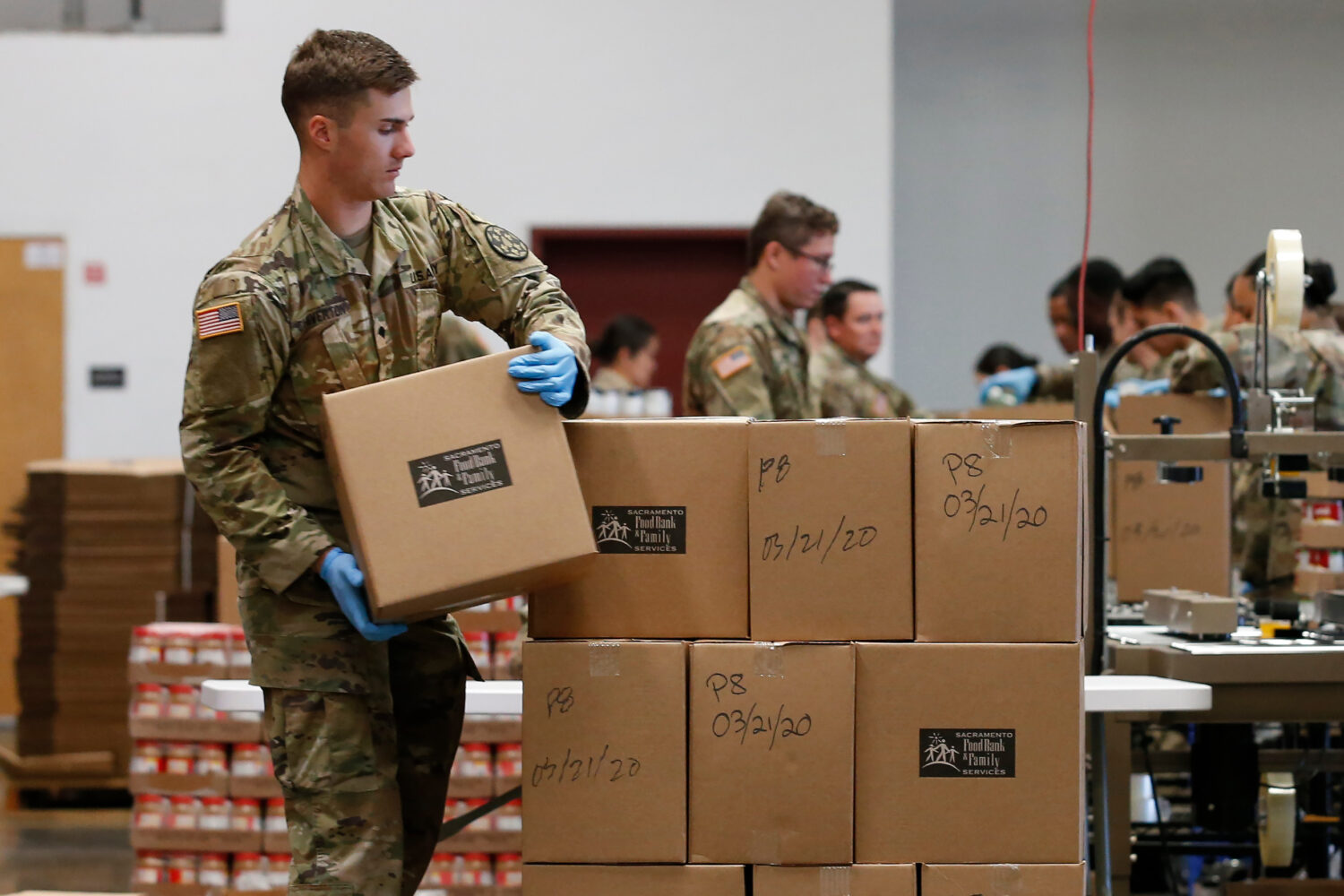 FILE - Specialist Colby Chiverton, of the California National Guard, stacks boxes of food supplies ...