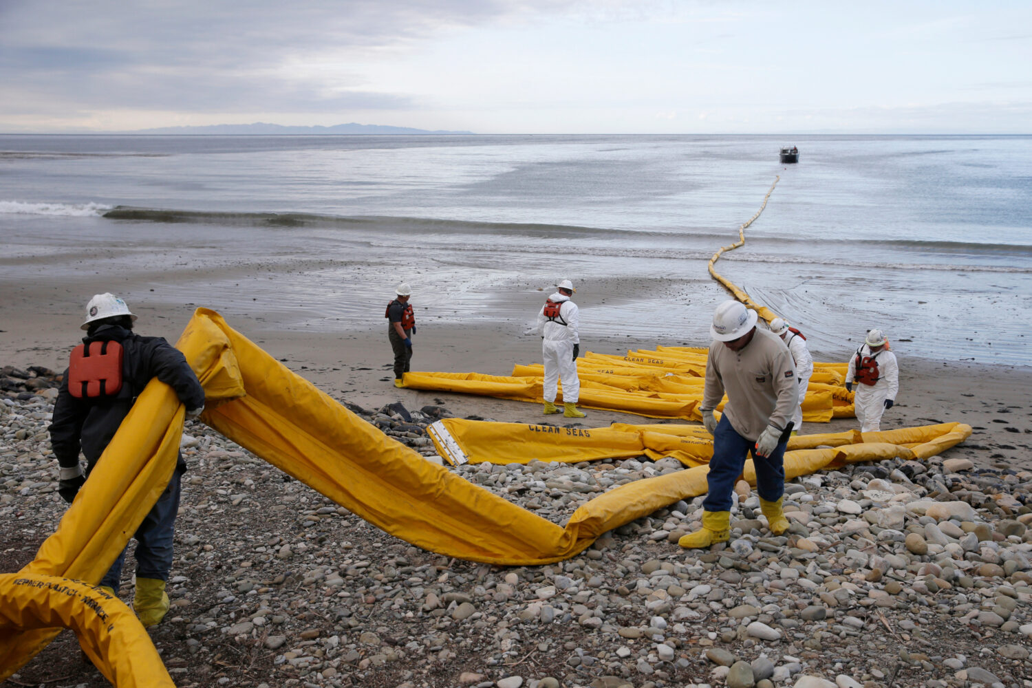 FILE - Workers prepare an oil containment boom at Refugio State Beach, north of Goleta, Calif., May...