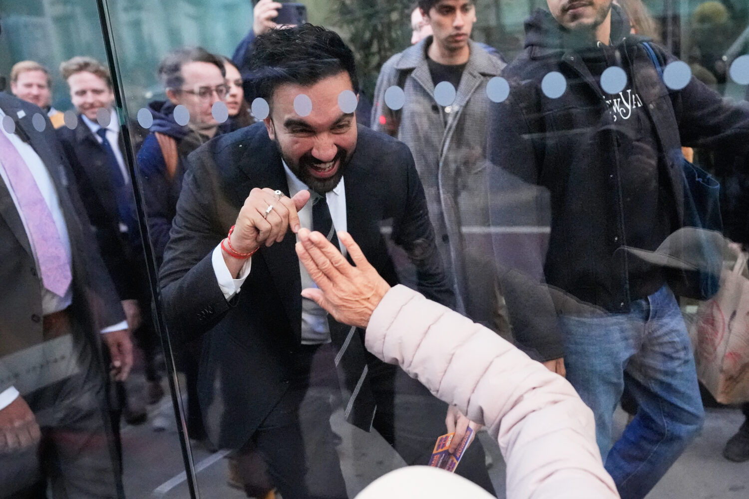 New York City mayoral candidate Zohran Mamdani waves to Rita Bellevue as she waits at a bus stop in...