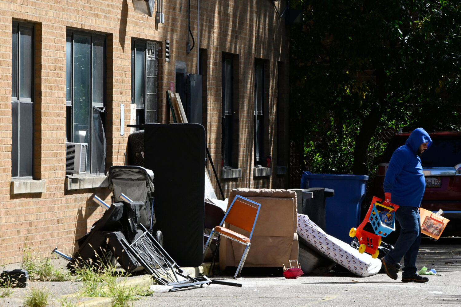 A worker throws away items, Oct. 8, 2025, after ICE agents raided the apartment building at 7500 So...
