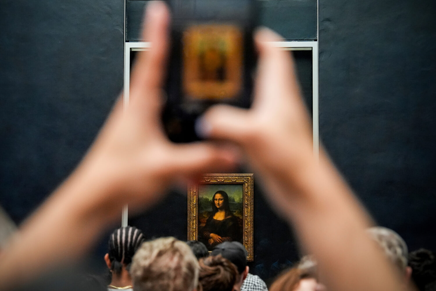 FILE - A person photographs Leonardo da Vinci's painting Mona Lisa at the Louvre museum, Aug. 31, 2...