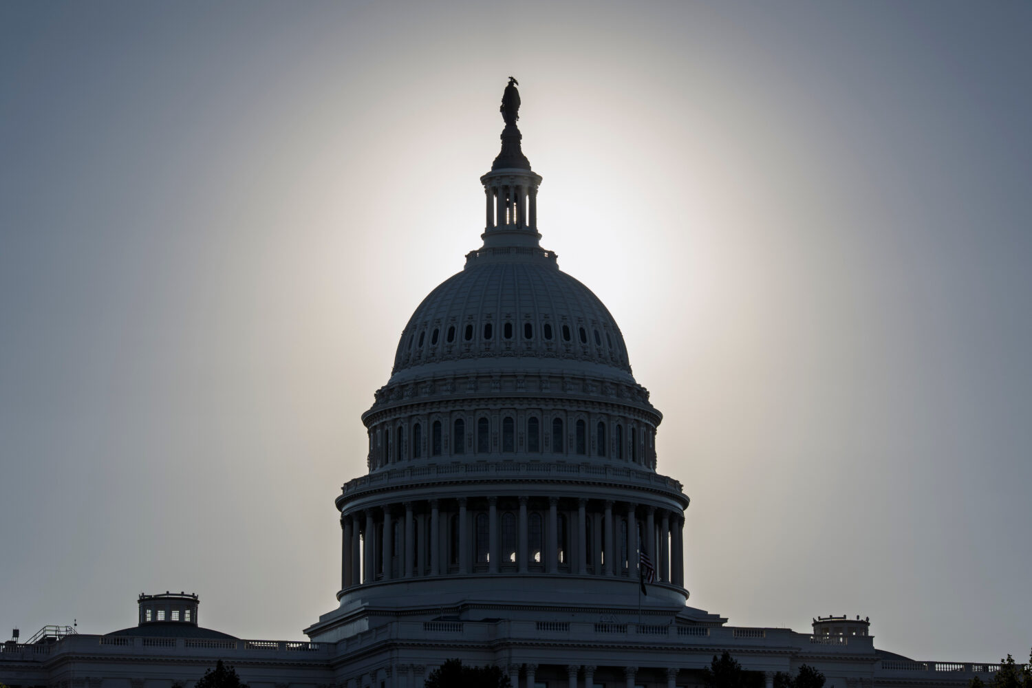 The Capitol is silhouetted by the stark glare of the morning sun as a government shutdown begins it...