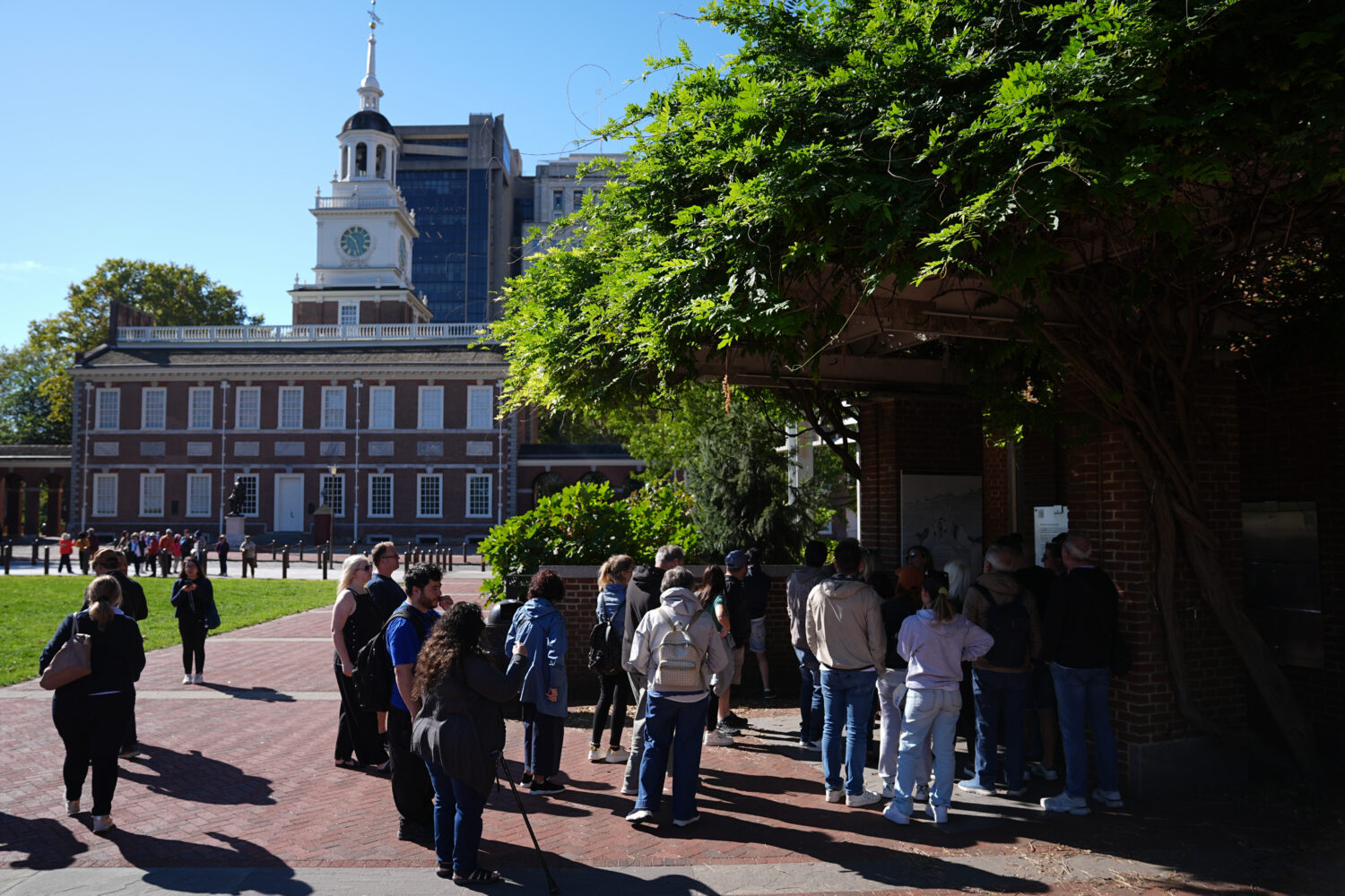 Tourist crowd around a window to view the Liberty Bell with Independence Hall in the background in ...