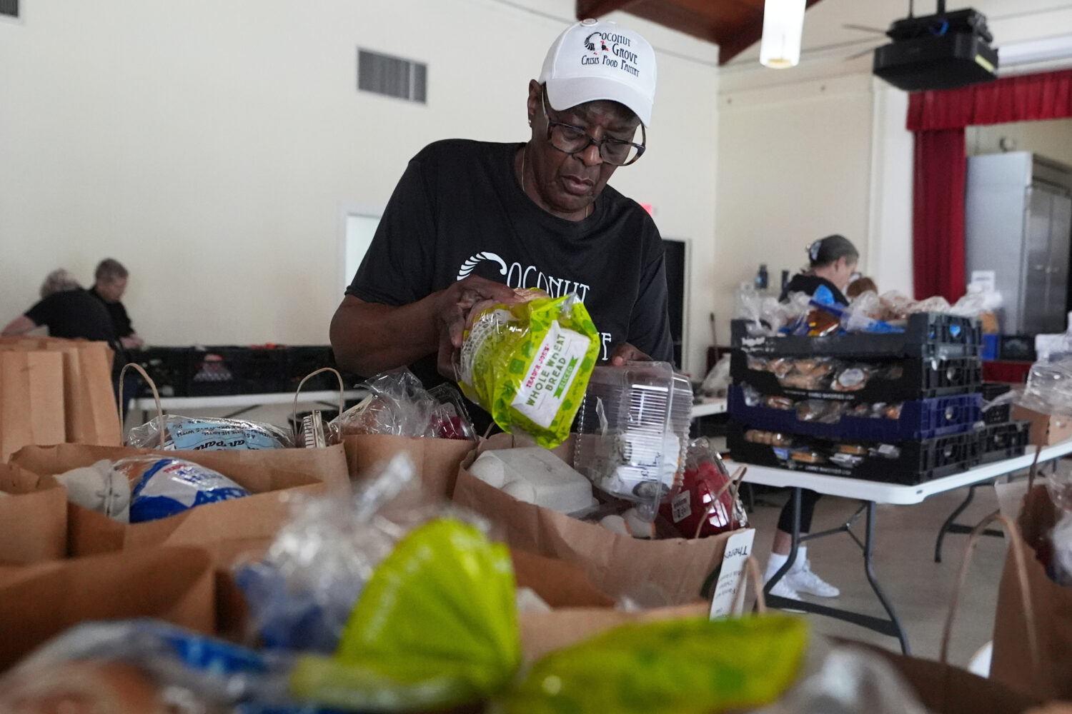 FILE - Volunteer Ollie Taylor fills bags with food at the Coconut Grove Crisis Food Pantry, which o...