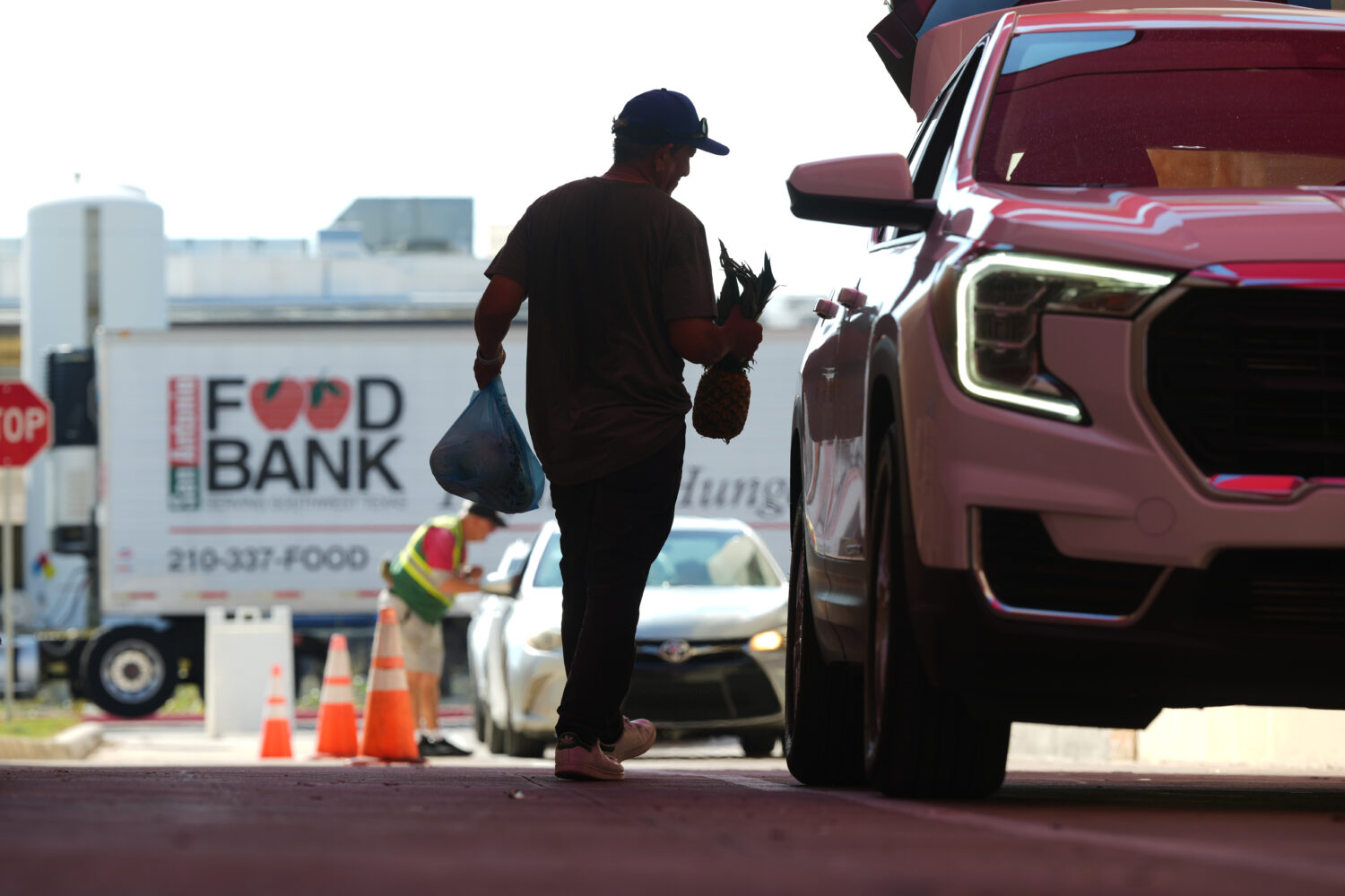 Volunteer Joel Hernandez helps load a vehicle during a food distribution targeting federal employee...