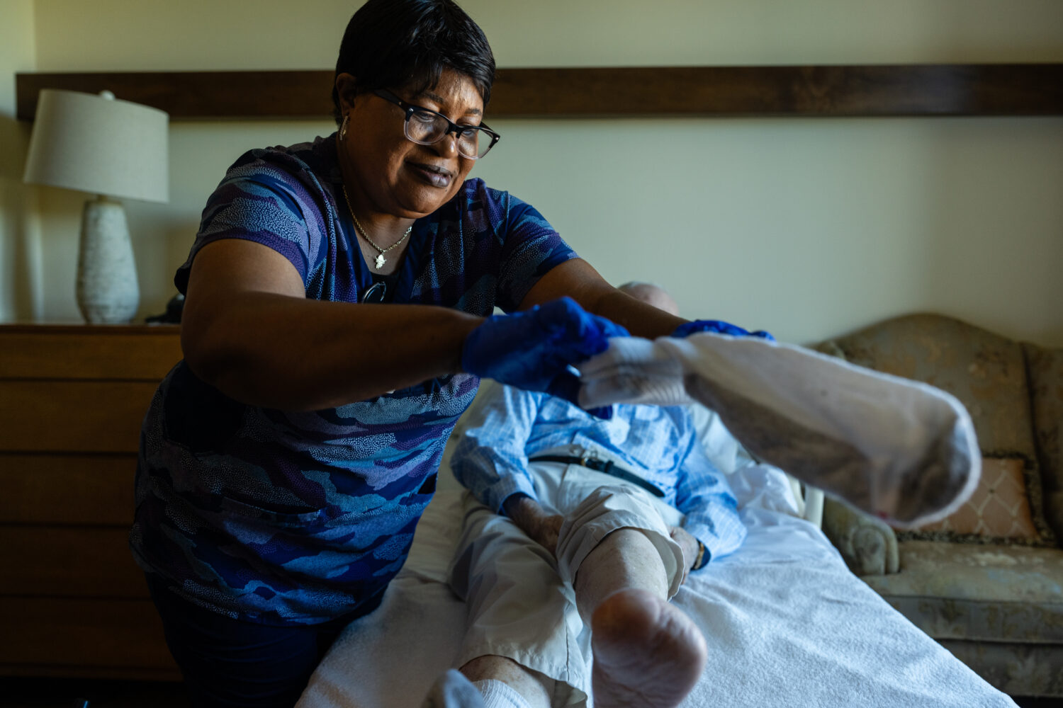 Jackie Conteh, an advanced care partner originally from Sierra Leone, helps Donald Goodness, 92, pu...