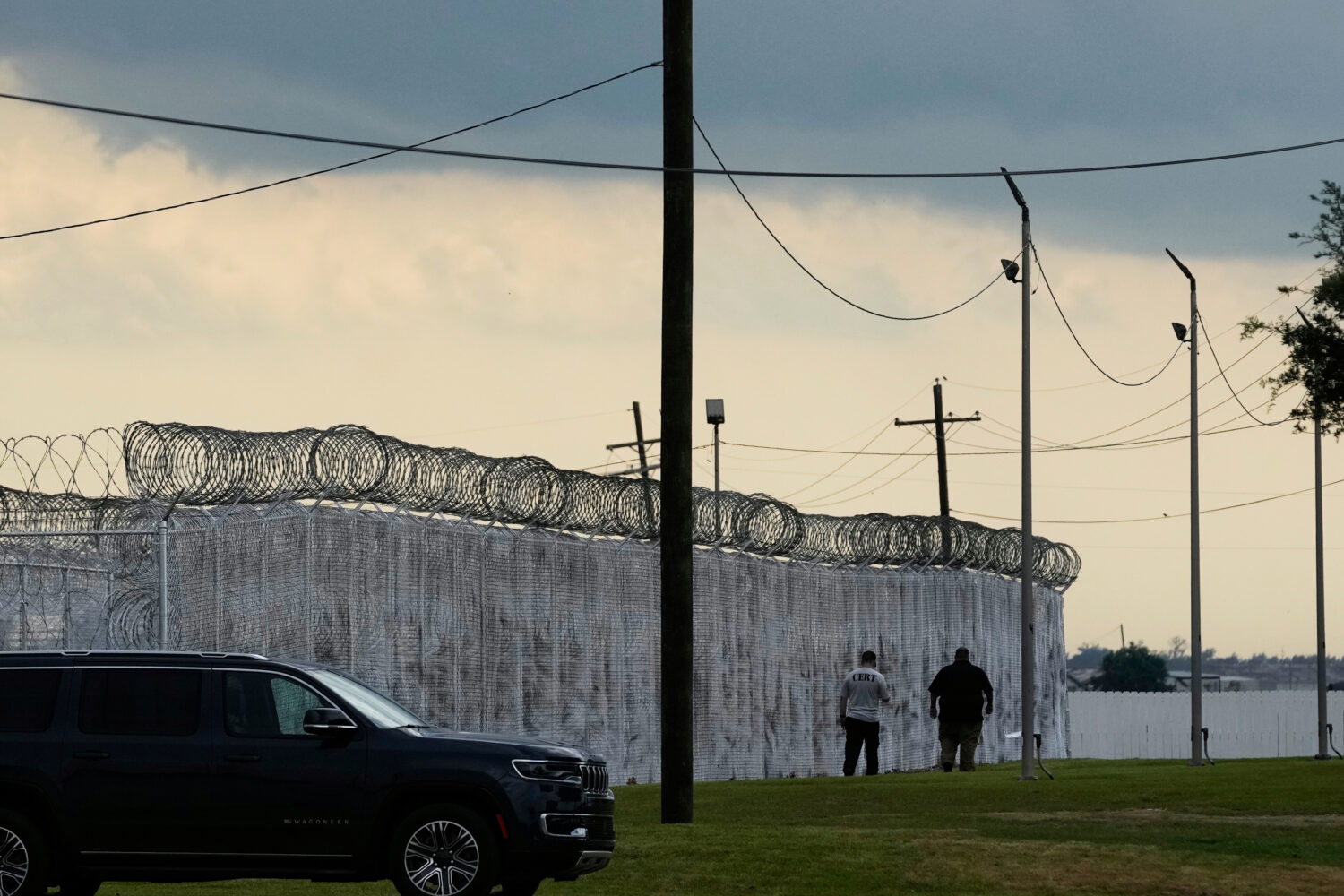 FILE - Security walk outside "Camp 57," a facility to house immigration detainees at the Louisiana ...