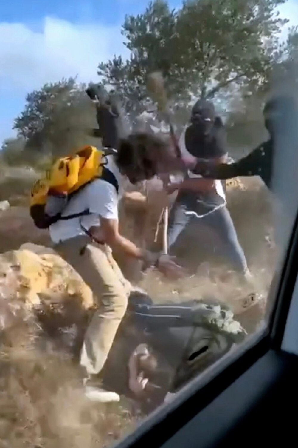 This Oct. 19, 2025, image taken from video shows what appear to be masked settlers beating activist...
