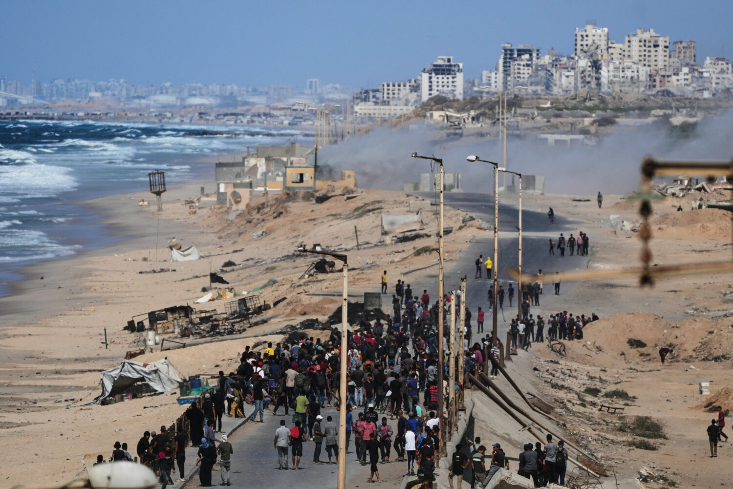 Displaced Palestinians gather on the coastal road near Wadi Gaza after the announcement that Israel...