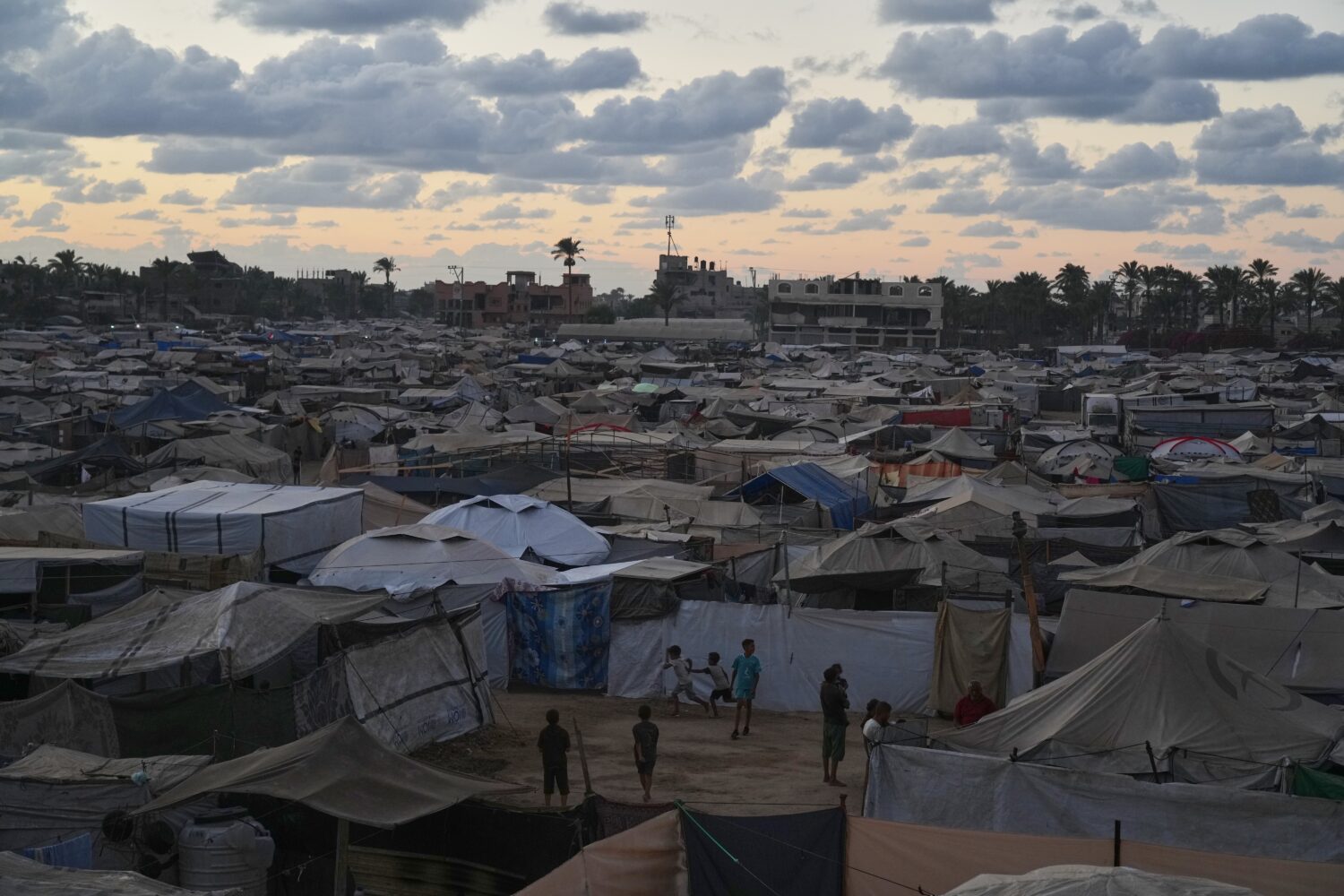 Dusk falls as children play at a temporary tent camp for displaced Palestinians in Deir al-Balah, i...