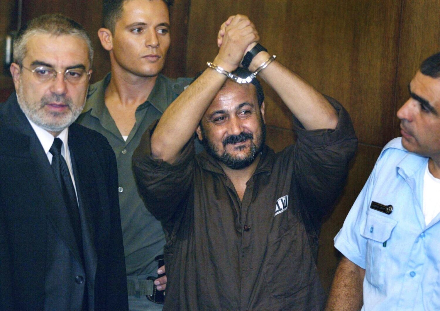 FILE - Marwan Barghouti, center, raises his handcuffed hands in the air on the opening day of his t...