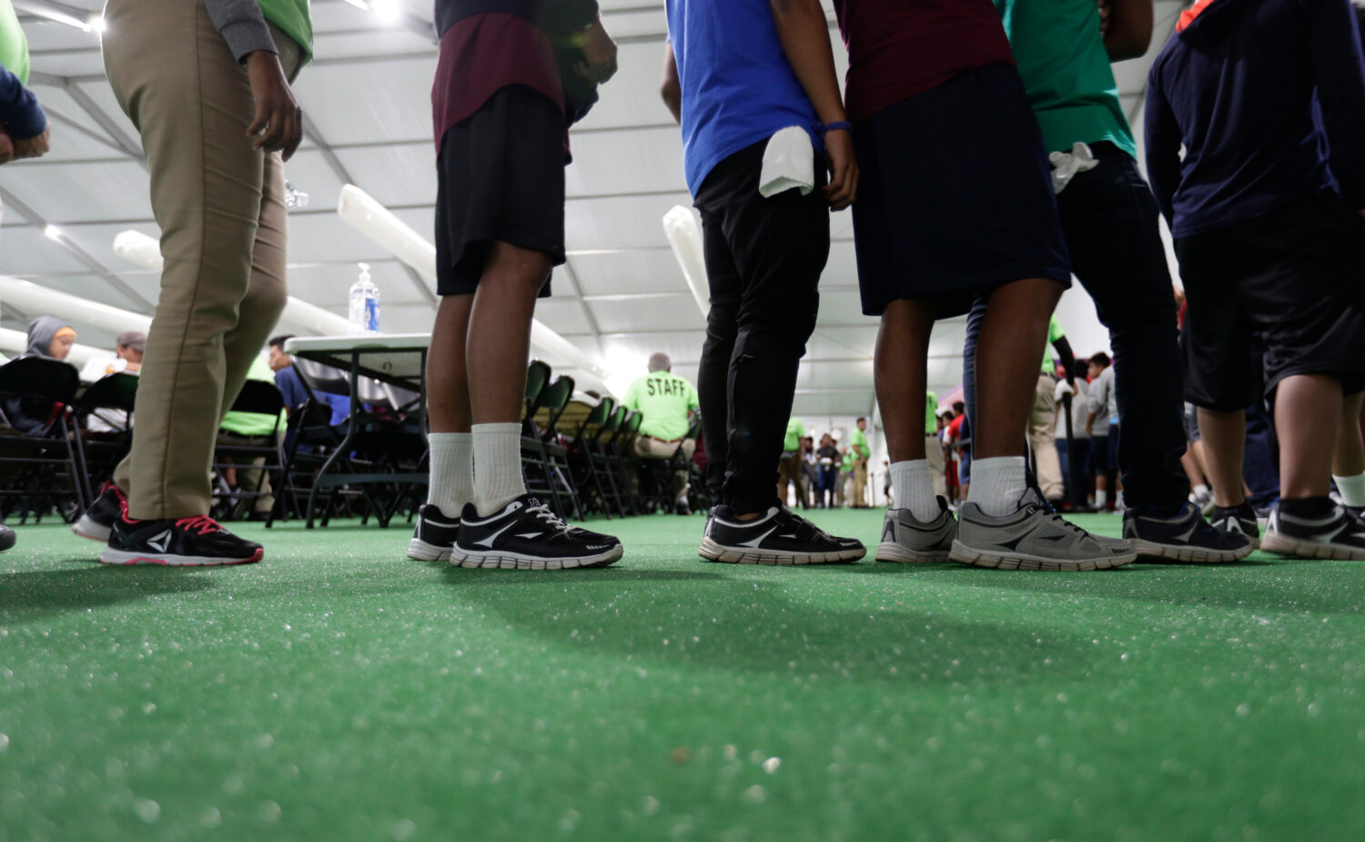 FILE - Immigrants line up in the dining hall at a new U.S. government holding center for migrant ch...