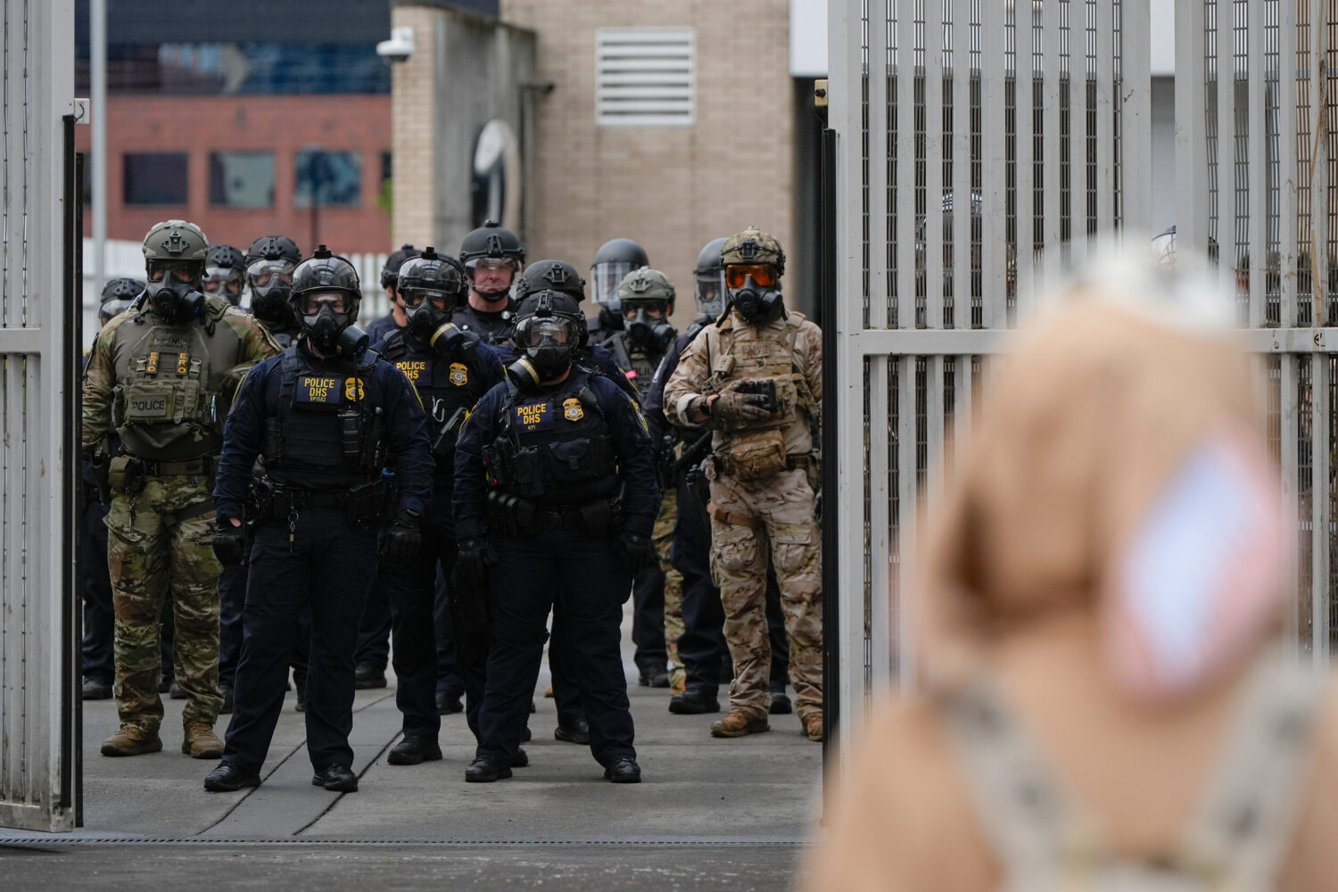 Law enforcement officers watch as the gates close at a U.S. Immigration and Customs Enforcement fac...