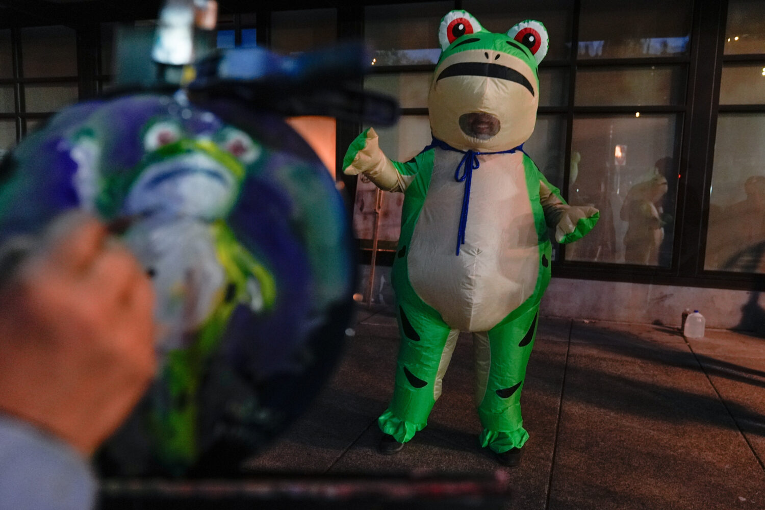 A person paints a portrait of a demonstrator dressed in an inflatable costume outside a United Stat...