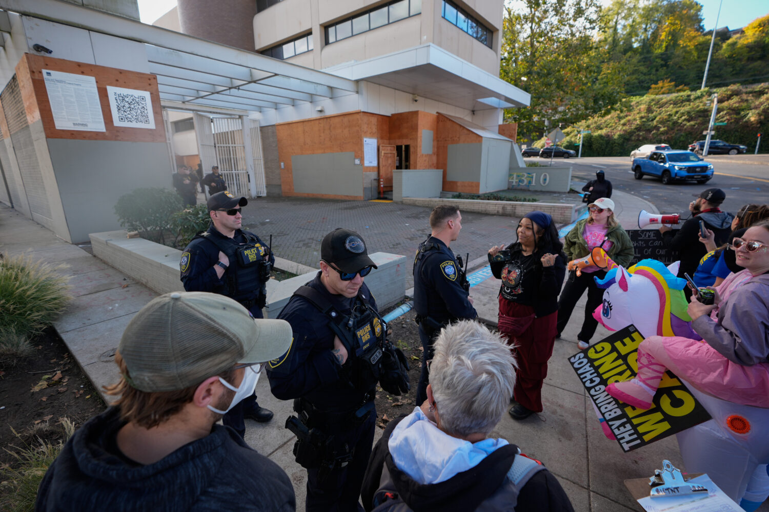 Law enforcement officers talk with protesters outside a United States Immigration and Customs Enfor...