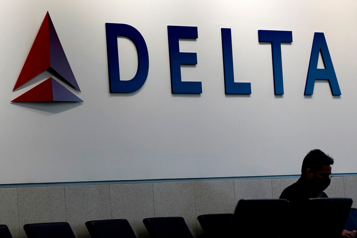 FILE - A man waits for a Delta Airlines flight at Hartsfield-Jackson International Airport in Atlan...