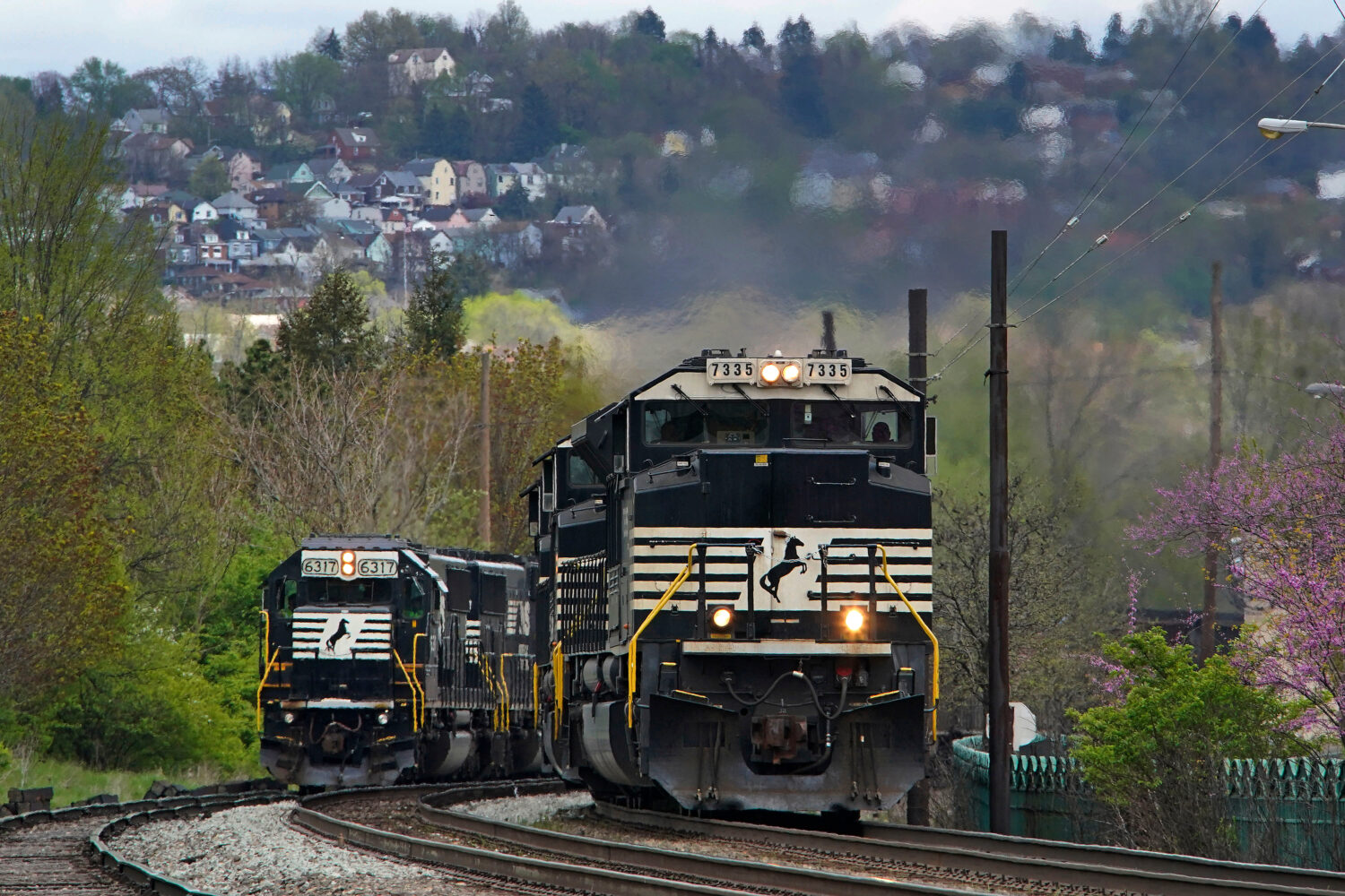 FILE - A Norfolk Southern freight train passes a train on a siding as it approaches a crossing in H...