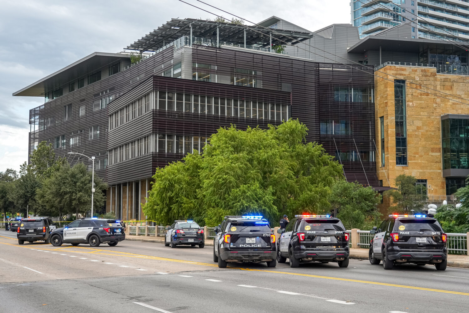 Police vehicles block the street after reports of a shooting at the Austin Public Library on César...