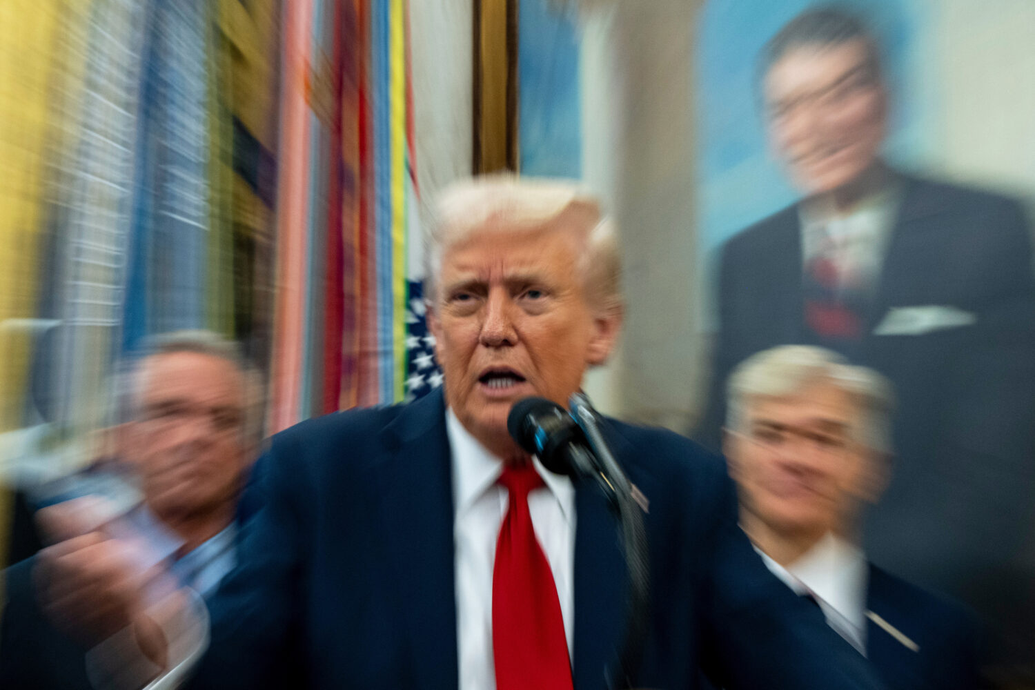 In this photo made with a slow shutter speed, President Donald Trump speaks in the Oval Office of t...