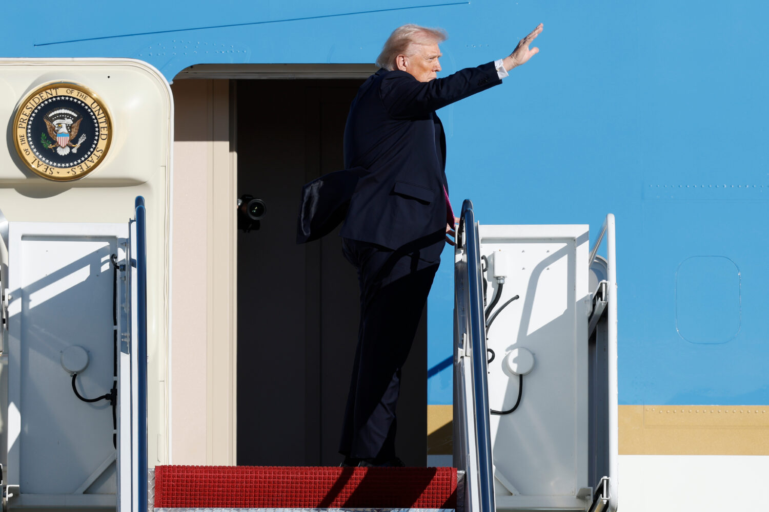 President Donald Trump waves from the stairs of Air Force One as he boards upon his arrival at Join...