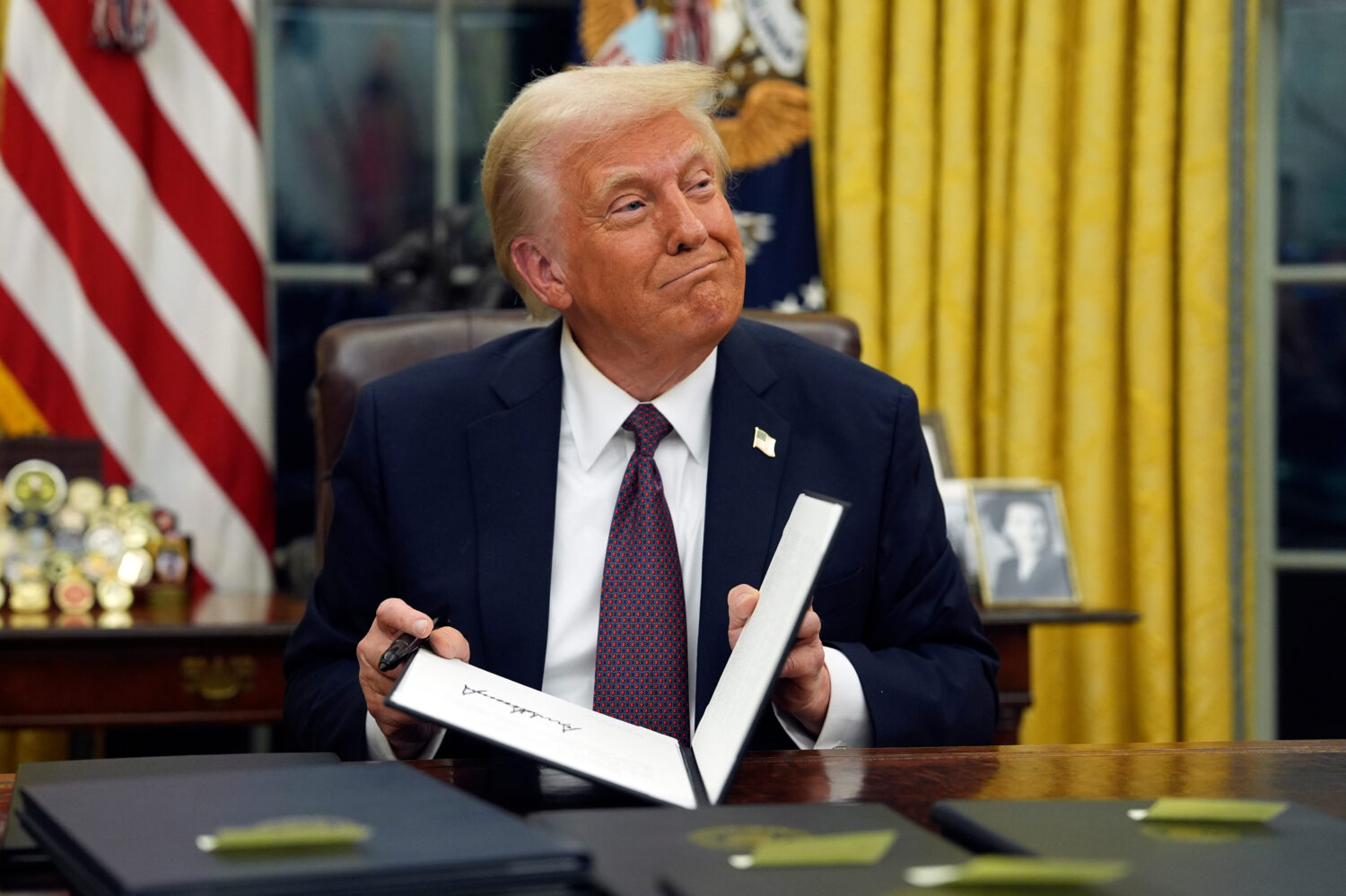 FILE - President Donald Trump signs executive orders in the Oval Office of the White House, Jan. 20...