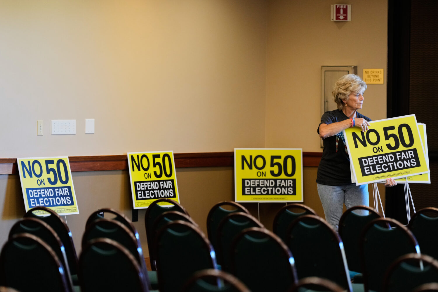 Brenda Haynes places signs throughout a conference room before a No on Prop 50 rally in Redding, Ca...