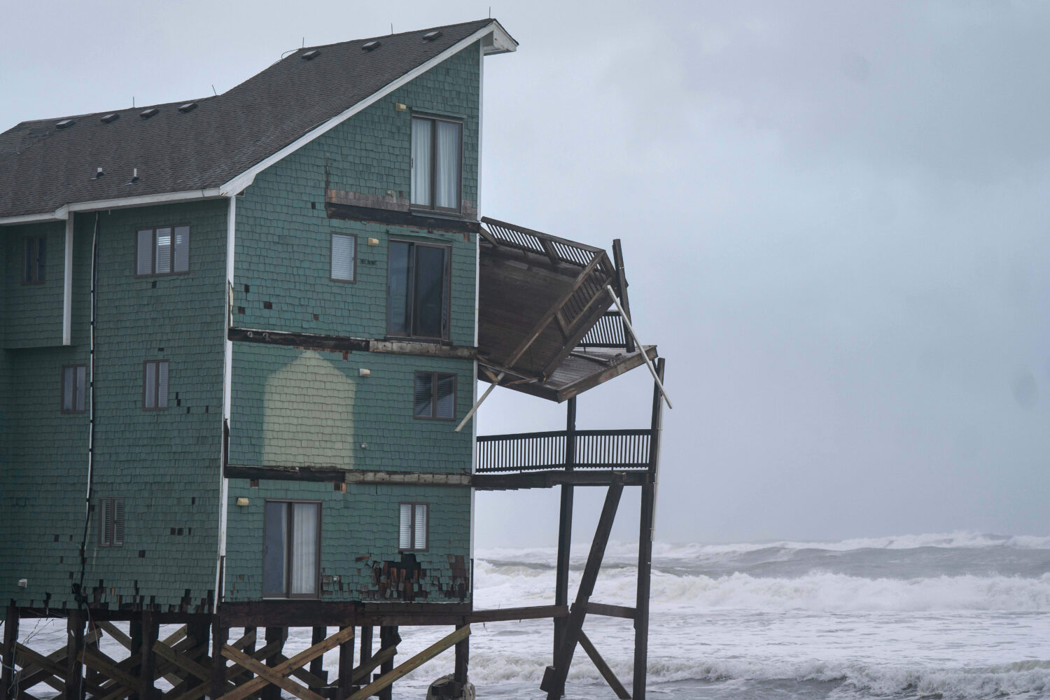 A balcony hangs off a home at risk of collapse in the midst of a storm, Sunday, Oct. 12, 2025, in B...