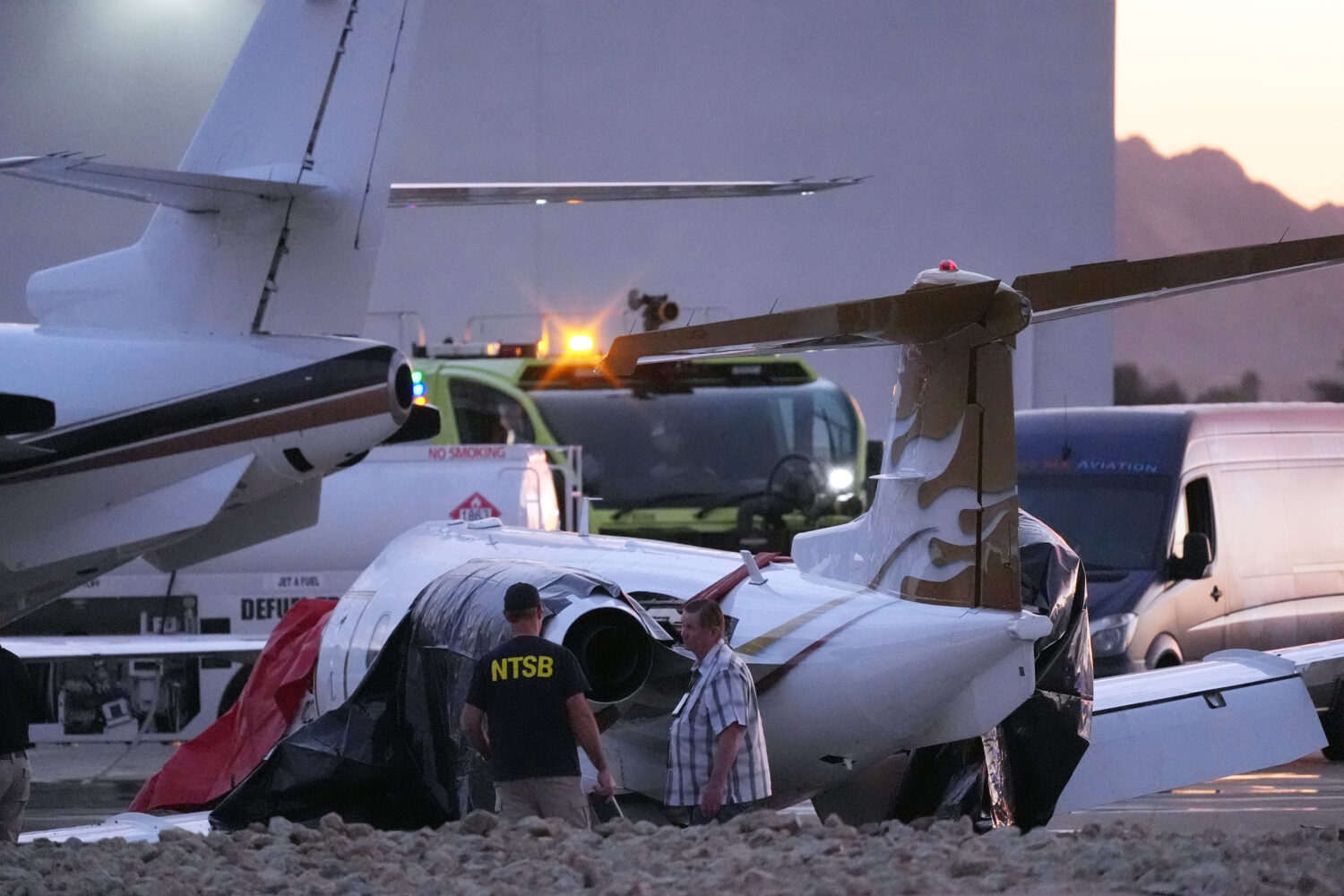 FILE - Investigators look at a crashed Learjet at Scottsdale Airport after it collided with a parke...
